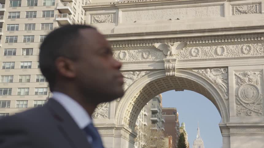 Man stands outside a large building in a city
