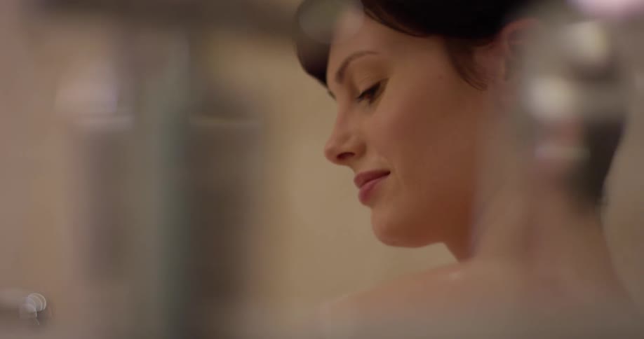 Woman rubs her neck and shoulder as she bathes