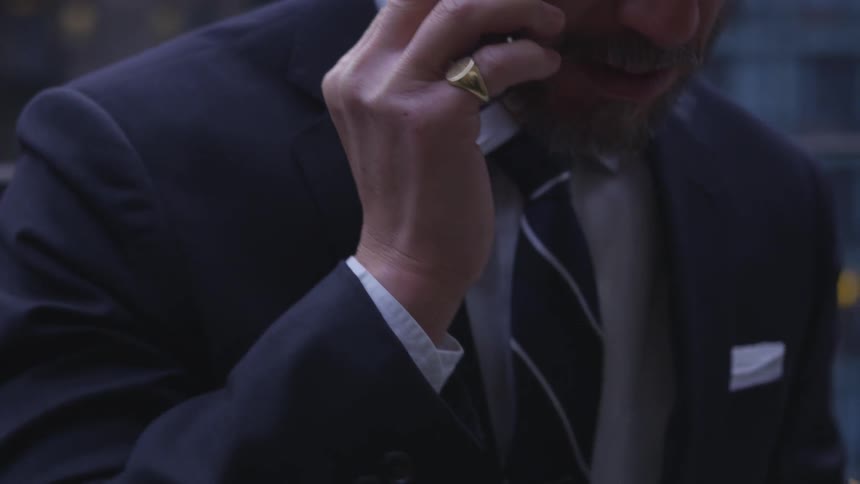 A businessman talks on a phone on a balcony