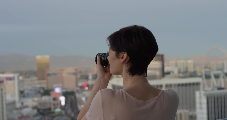 Woman takes a photo of the city under a blue sky