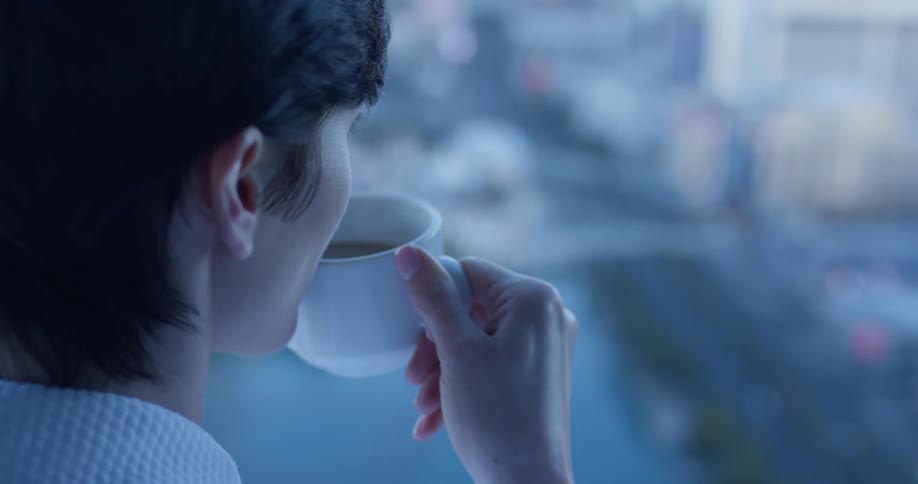 Woman holds a coffee cup as she looks out at the city
