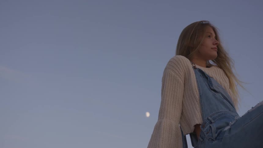 A woman is sitting as the sun sets