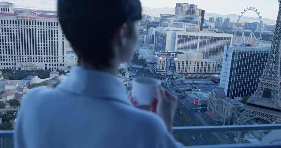 A woman takes a drink on the balcony