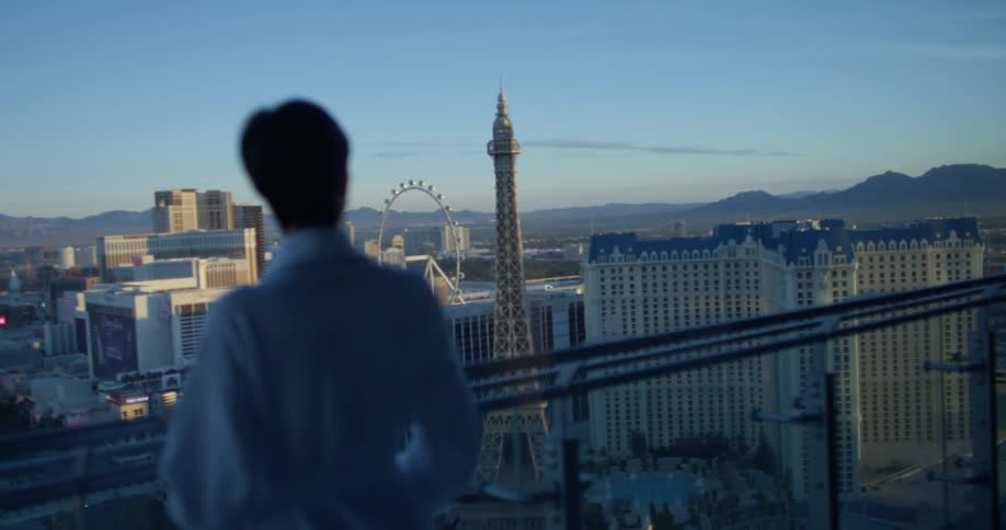 Woman in a white bathrobe looks out at the city