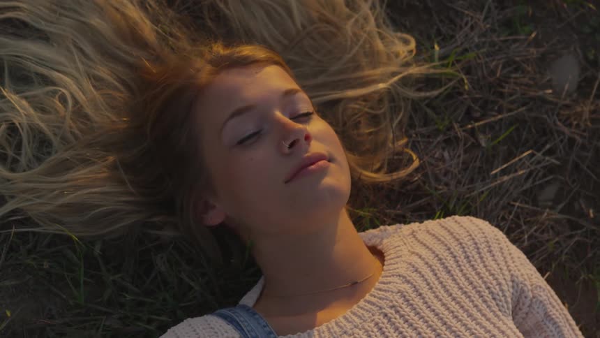 A woman is smiling as she rests in the grass