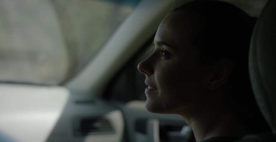 A woman laughs as she sits in a car