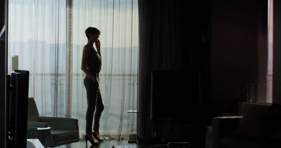 Woman talks on the phone while standing in front of a large window