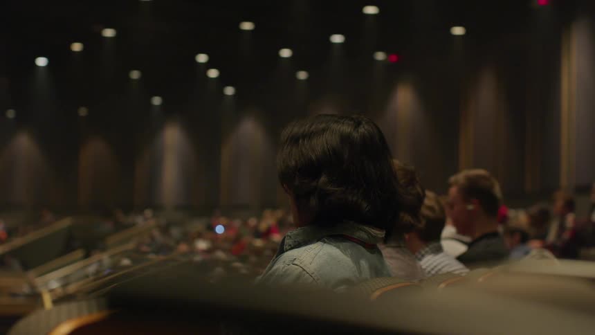 People sit in the auditorium watching on