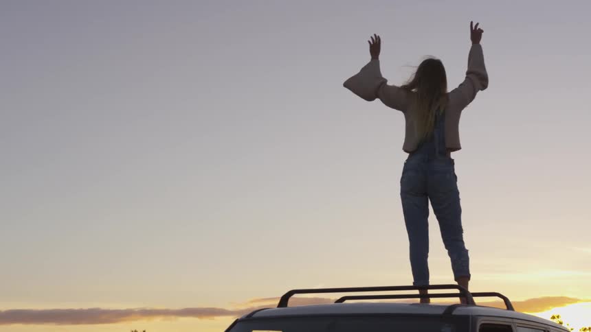 A woman is standing on the vehicle waving her arms