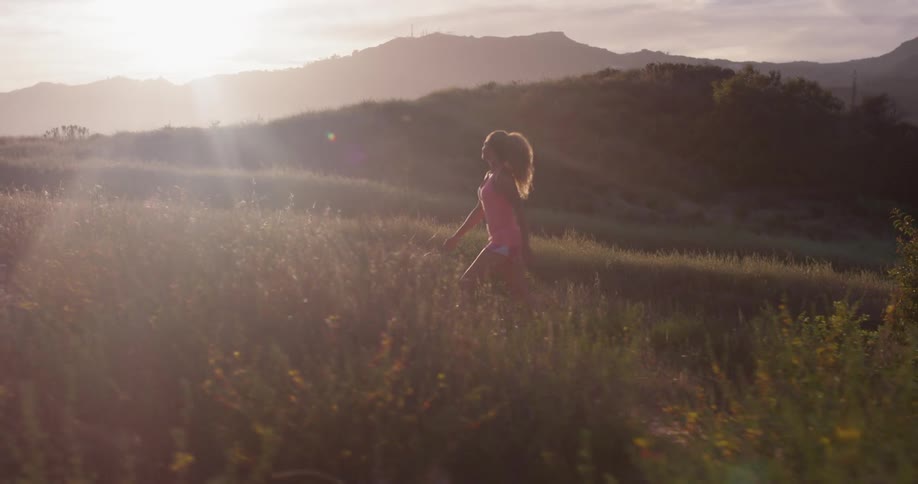 The woman is walking uphill in the grass