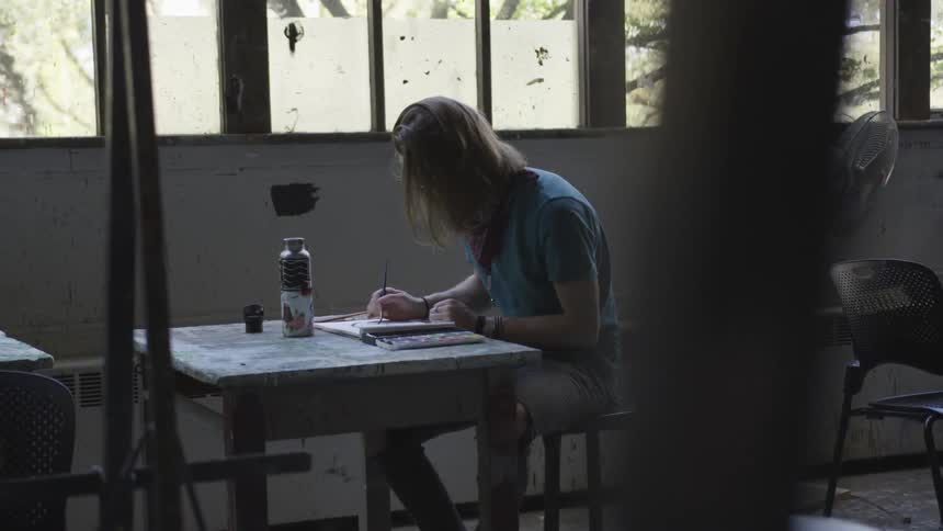 A man painting on a table next to a window