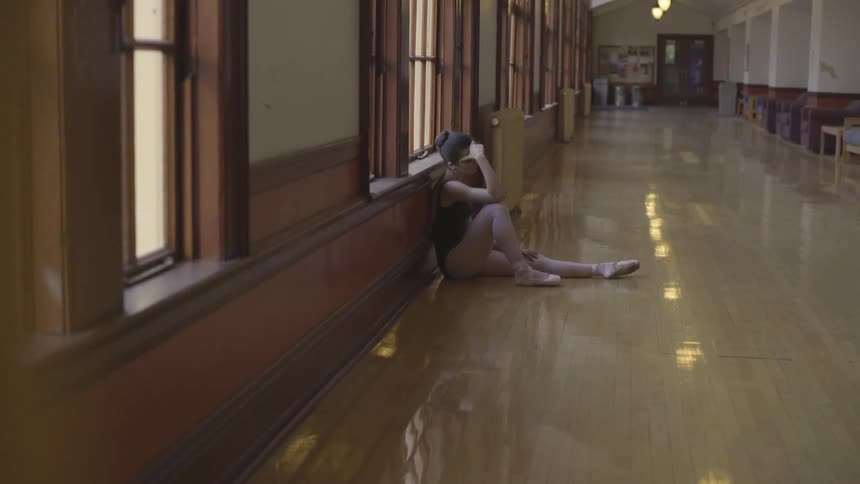 A woman sits on the floor by the window