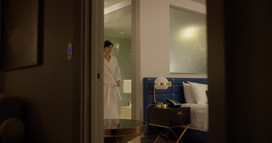 A woman wears a robe in a hotel room