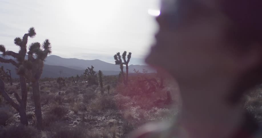 A woman stands in a desert on a sunny day