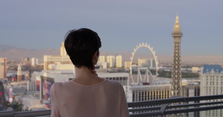 Woman stands on a balcony looking at the city below