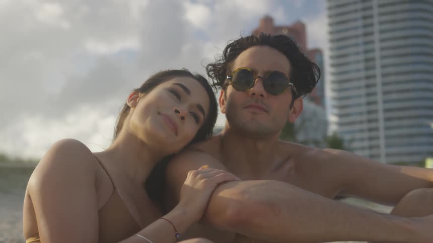 Woman hugs a man while they sit outside on the beach