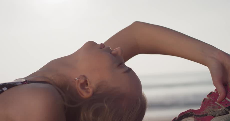 A woman is leaning back stretching on the beach