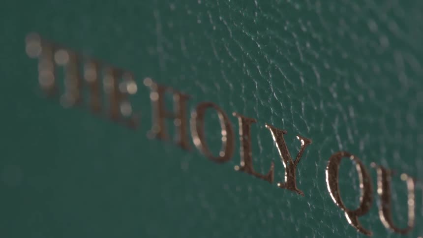 A closed copy of the quran is standing on a surface