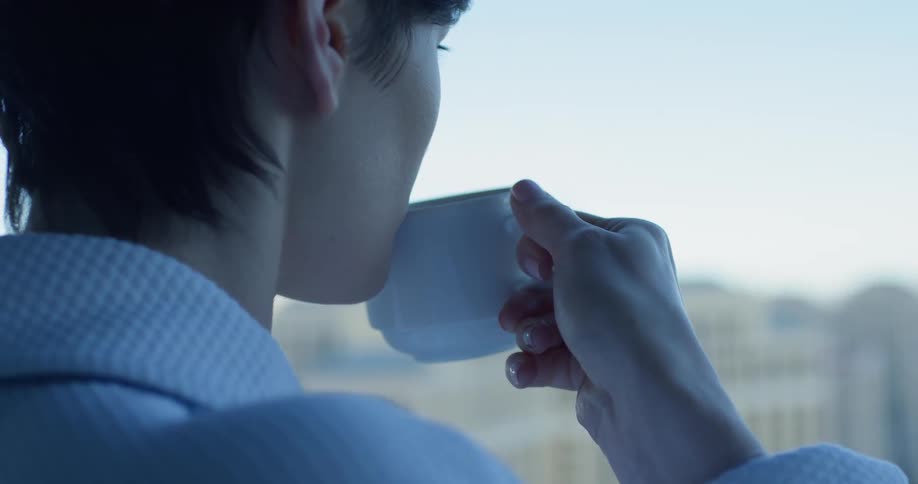 A woman drinks coffee on a hotel balcony