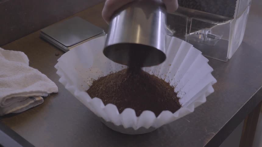 A person pours coffee into a white paper filter