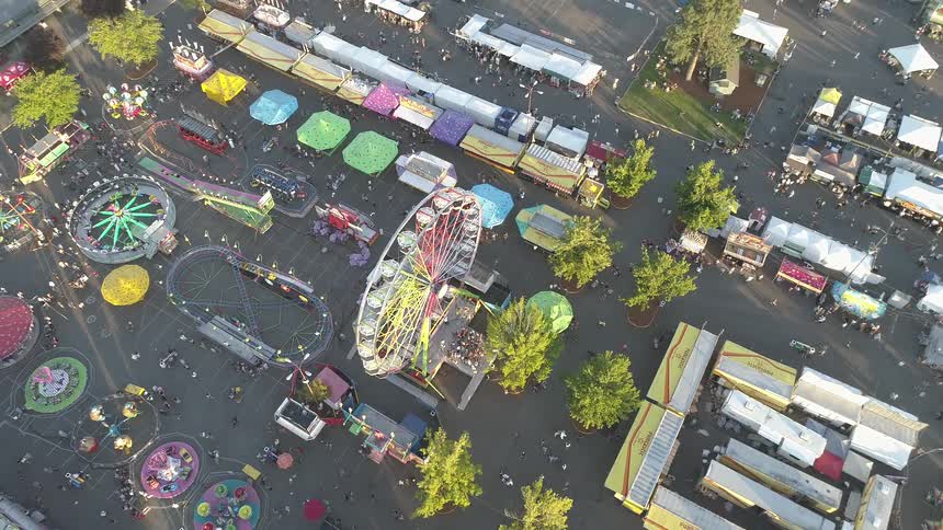 Fairgoers wander around a fairgrounds in daylight