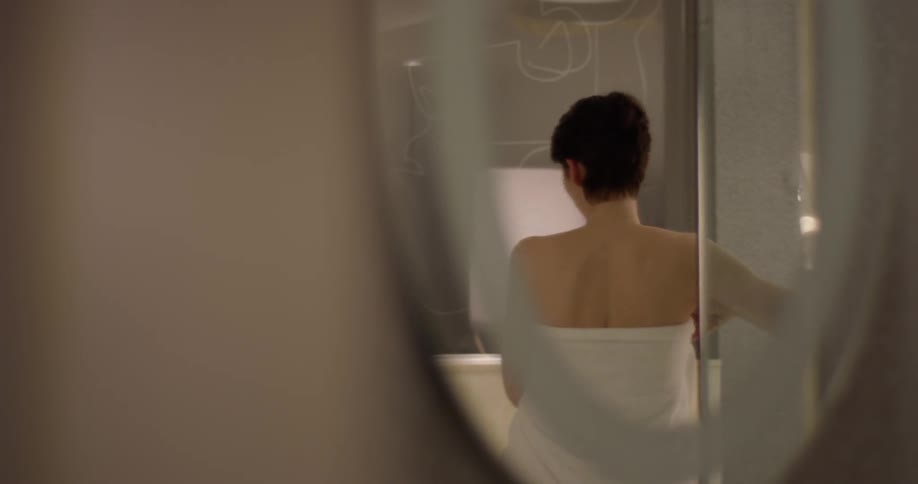 Nude woman wraps a towel around herself in the bathroom