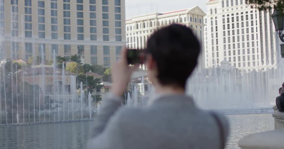 A woman takes a picture of fountains in las vegas