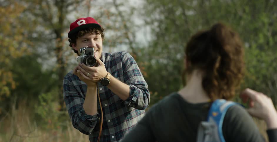 A man photographs a woman in the woods