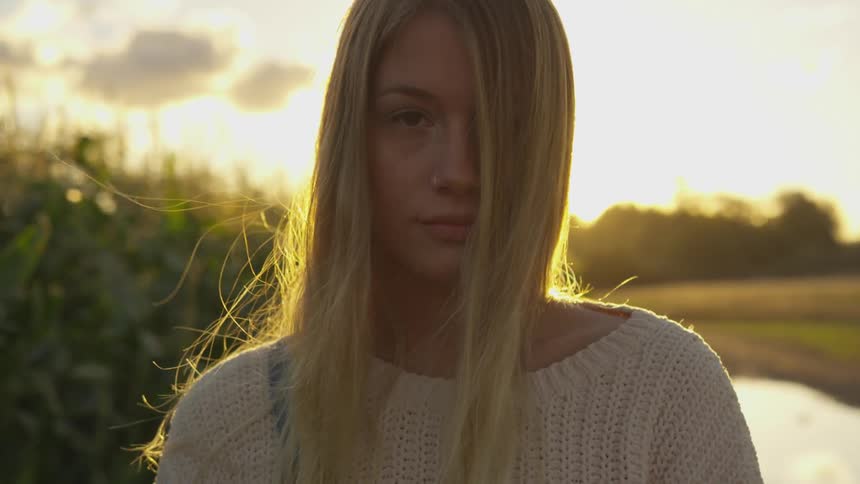 A woman stands by the fields on a windy day