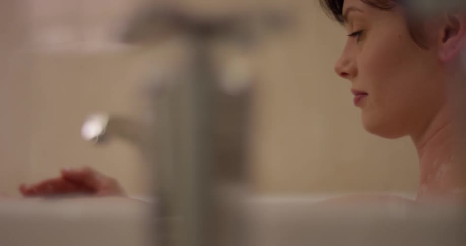 Woman rubs her neck and arm as she bathes