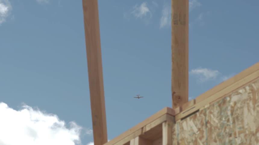 An airplane flies across the blue sky