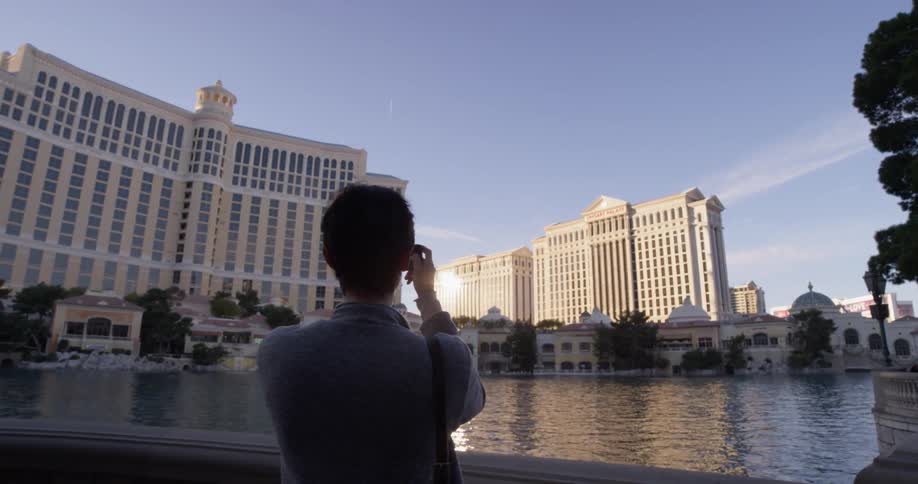 A woman takes photos with a camera by water in front of the buildings