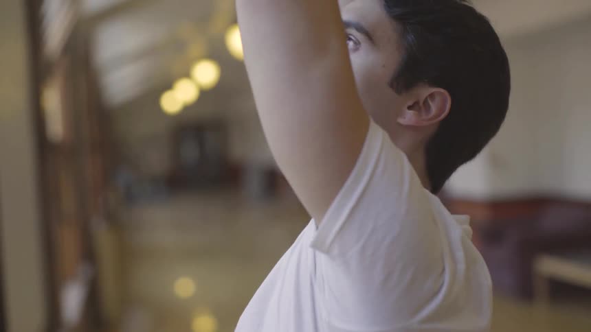 Man lifts his arms over his head in a long hallway