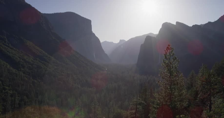 Sun shining over large granite rocks and forest trees in yosemite