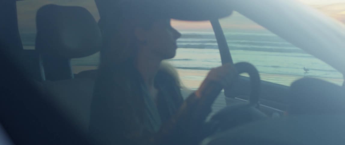 Woman gets into a parked car on the beach