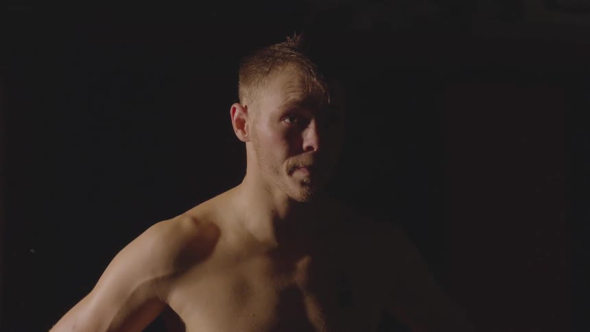 Man stands in a dim room with hands on his hips