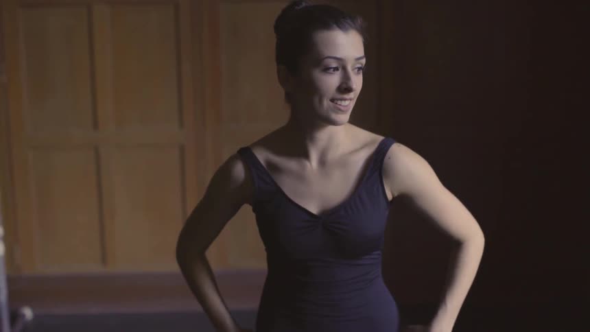 A woman adjusts her leotard in a dance studio