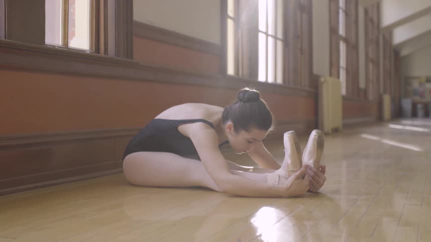 A ballerina stretches in a dance studio