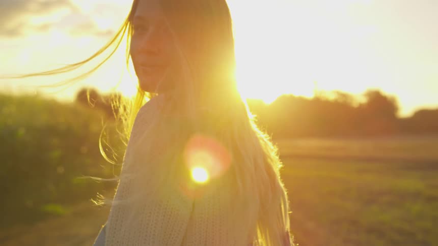 A woman is walking on a windy day at sunset