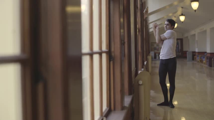 Man does stretches in a long hallway