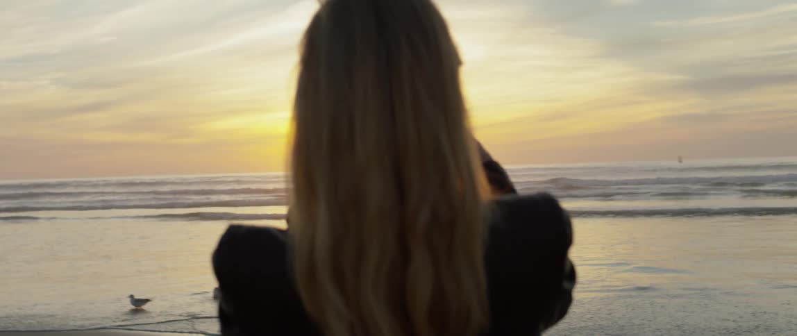 Woman takes a picture of the beach at sunrise