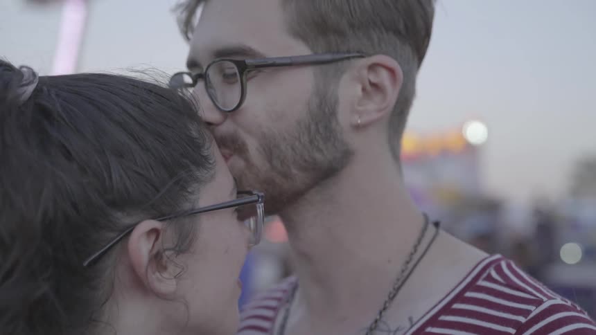 A man kisses a woman on the forehead at the carnival