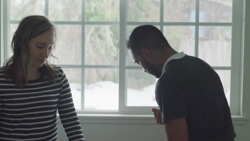 Man and woman talk next to a window with snow falling outside