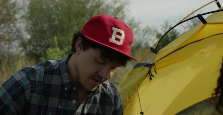A man and woman kneel next to a tent