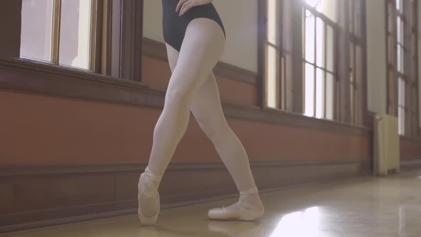 Woman practices ballet dancing in a sunny room
