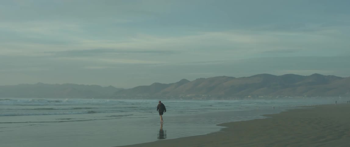 Person walks on the beach on a cloudy day