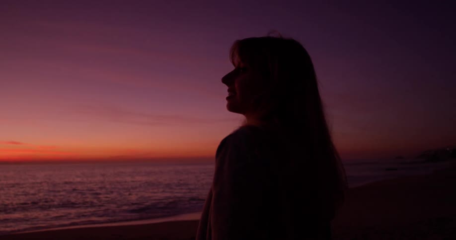 A woman watches the waves at dawn