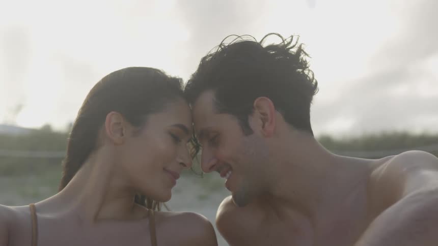 Man and woman sit together outside on the beach