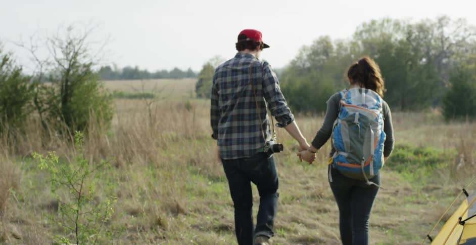 A man and woman are holding hands and hiking in the woods