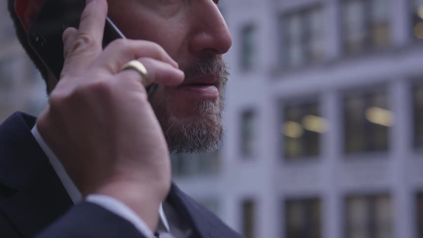 A man talks on his phone and nods in the city